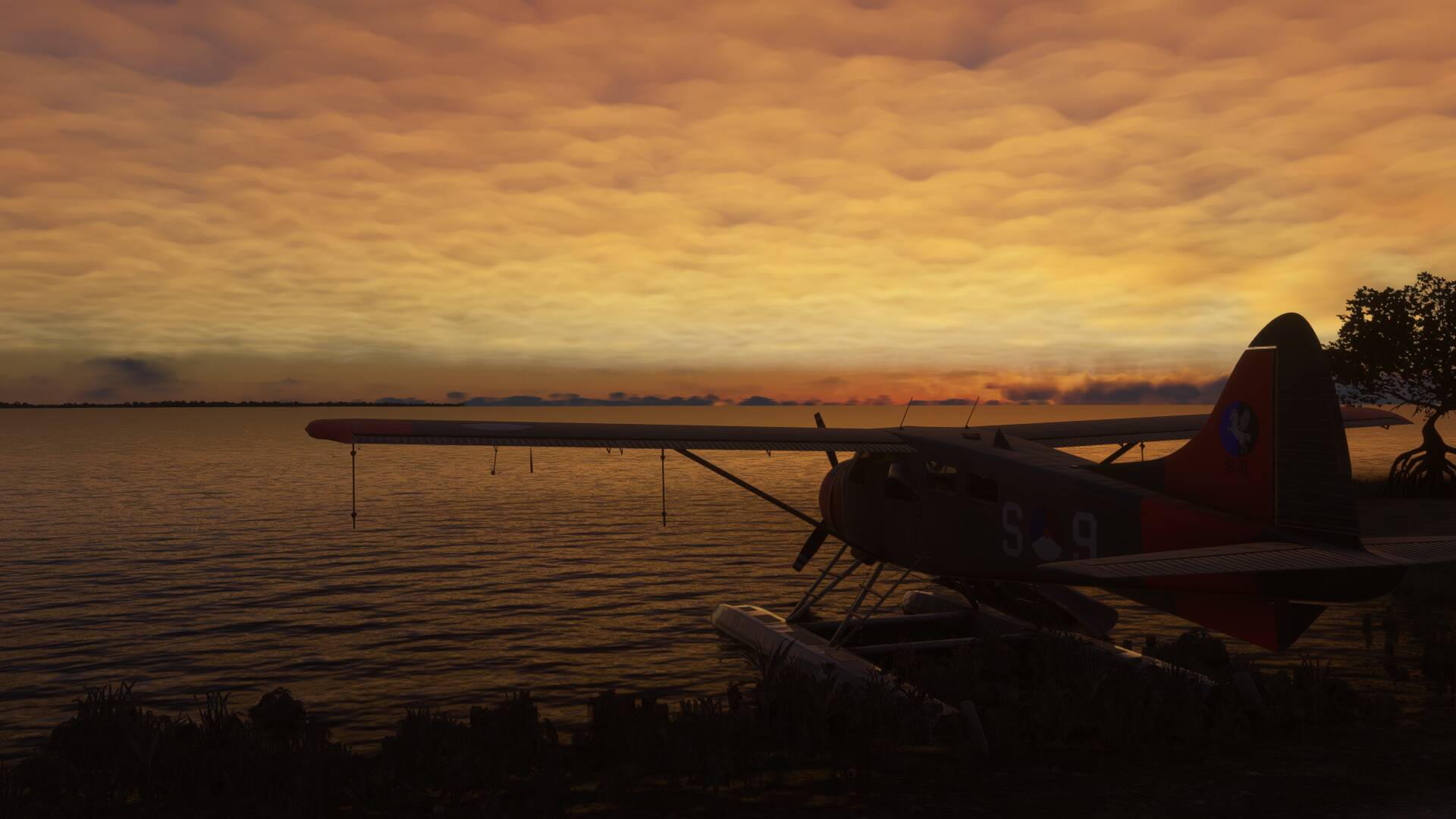 A high wing propeller aircraft sits idle on its water skis after sunset