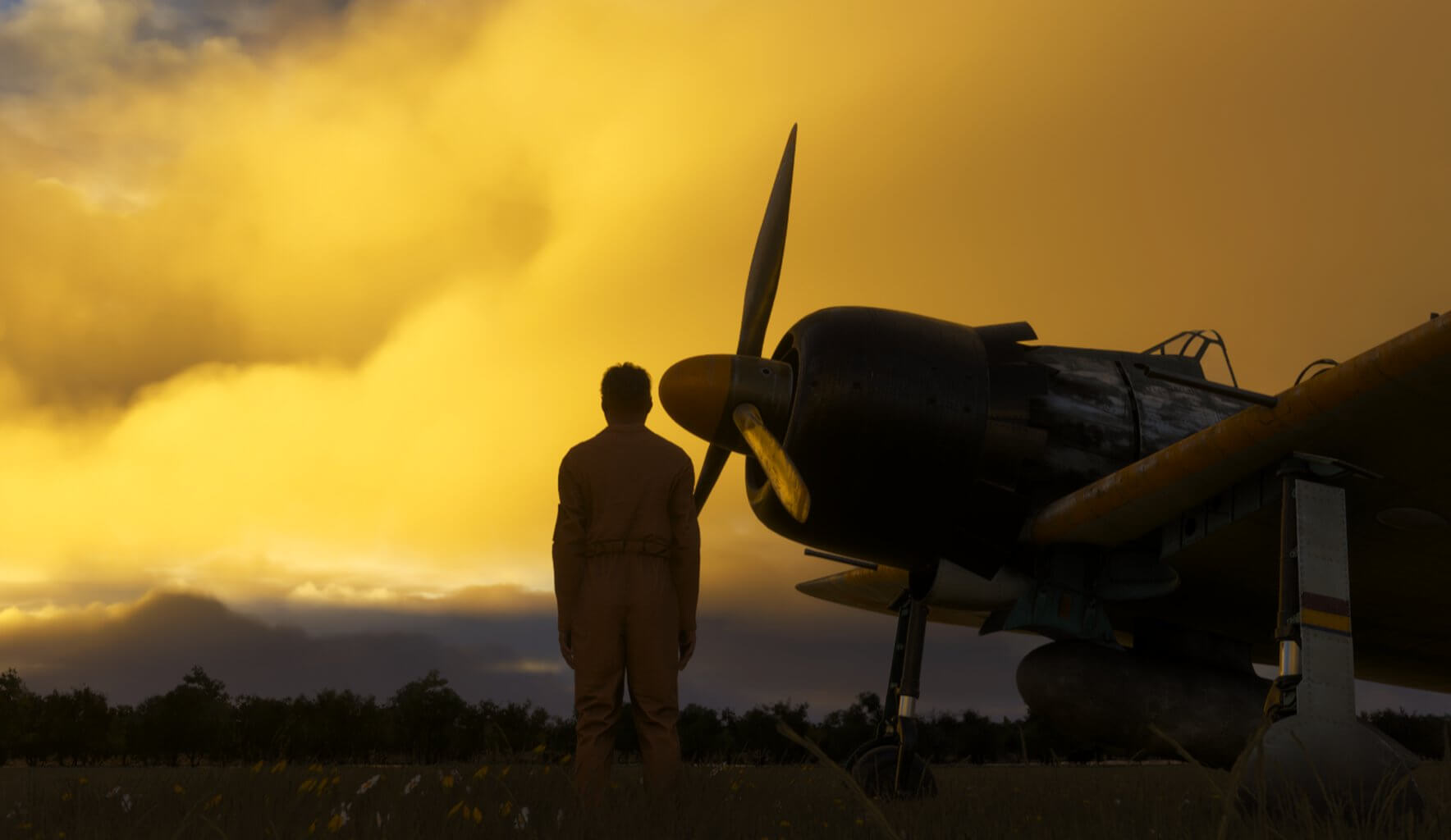 A pilot checks their aircraft during sunset