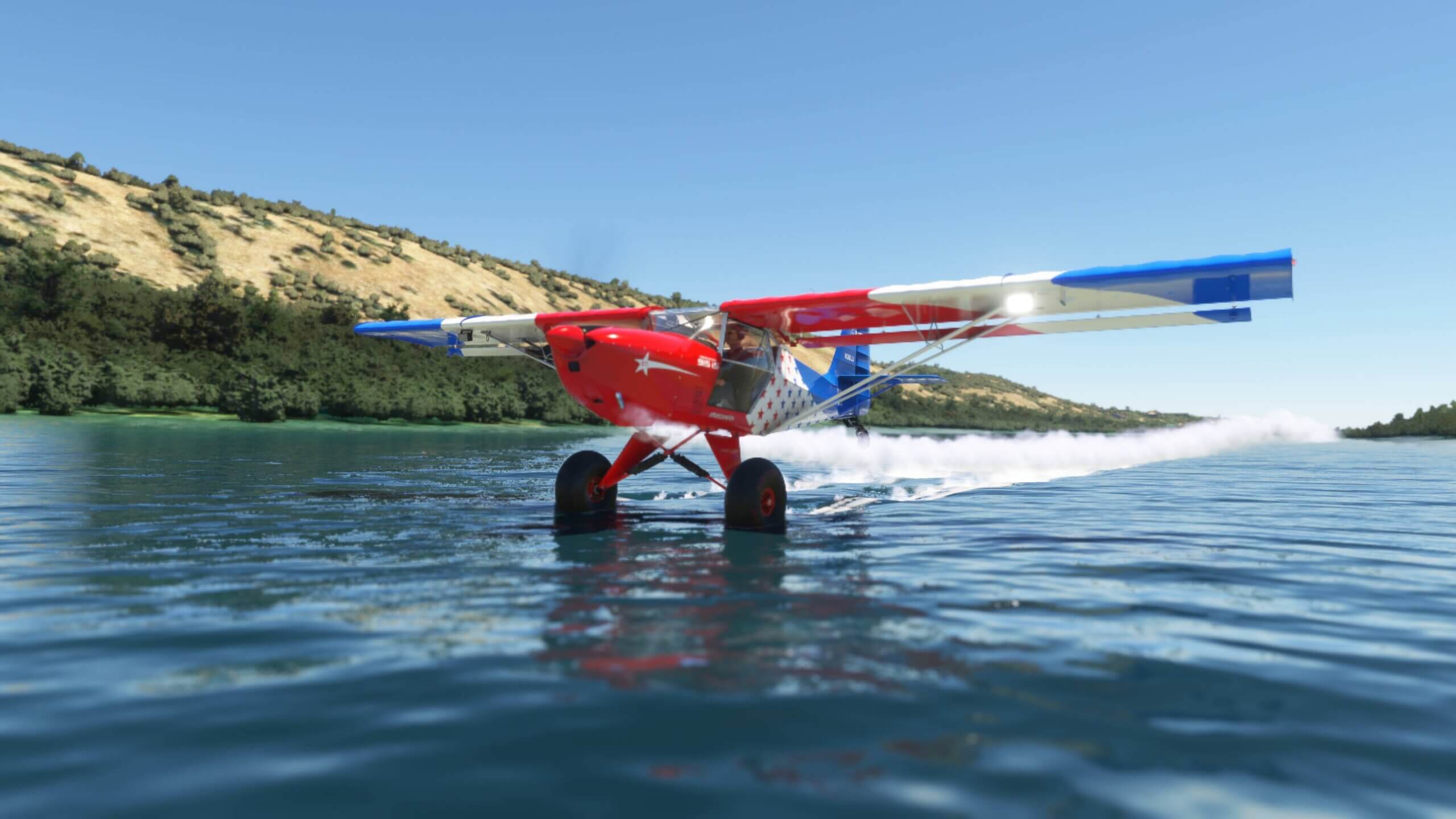 A bush plane skims the surface of a river, kicking up a wake of water behind it.