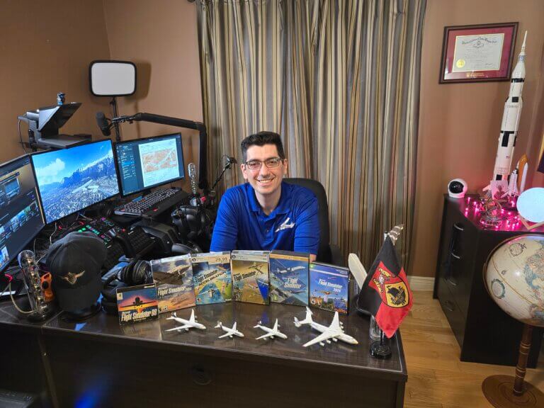 CaptArash sitting at his desk. There are boxes for many different versions of MSFS in front of him.