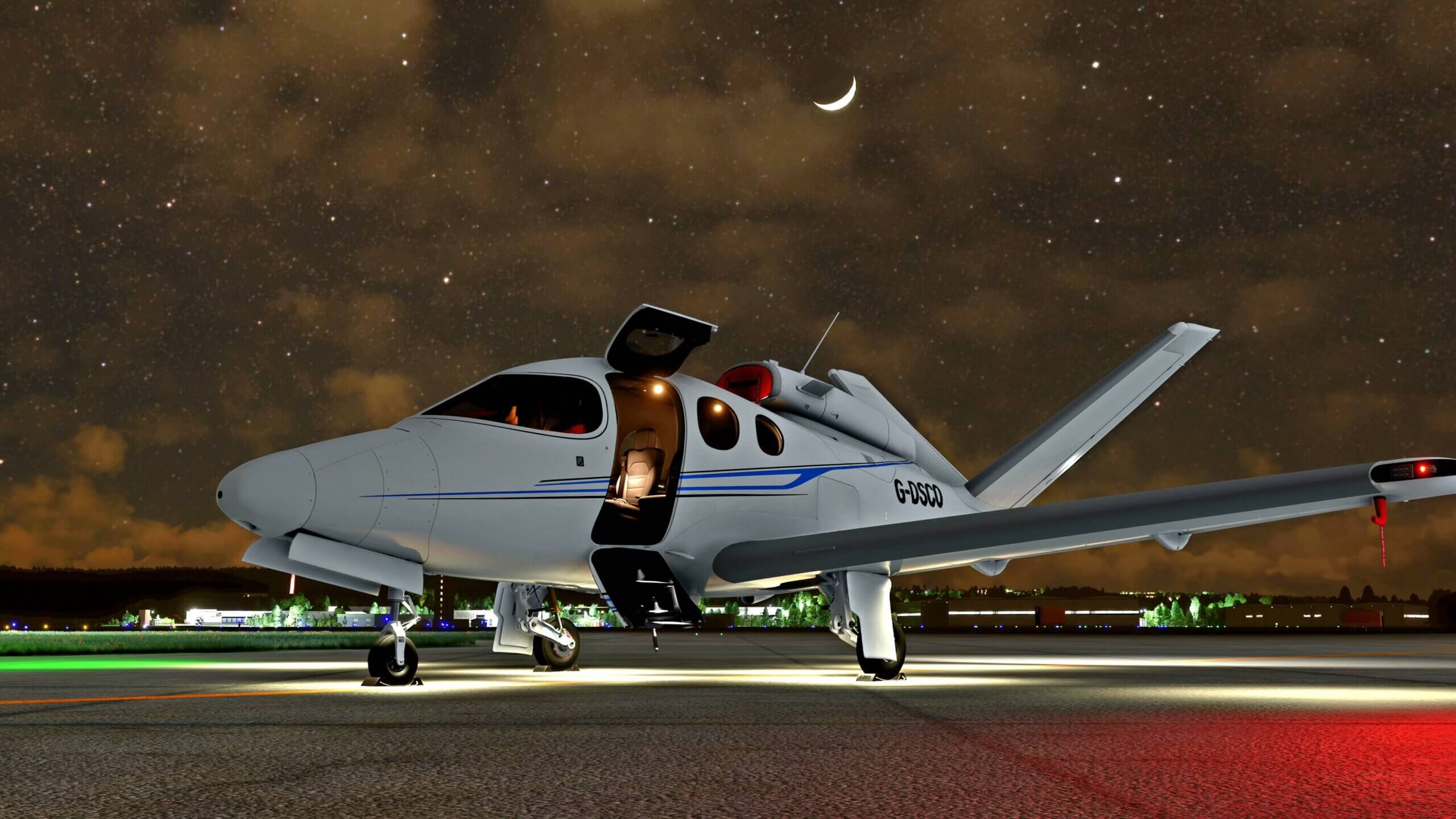A Cirrus Vision Jet sits idle on the ramp at night with the moon and stars in clear view above