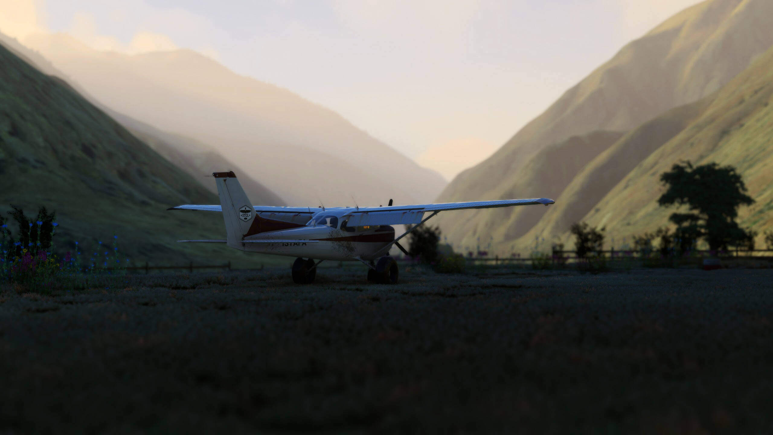 A cessna 152 sits on a grass field in a valley