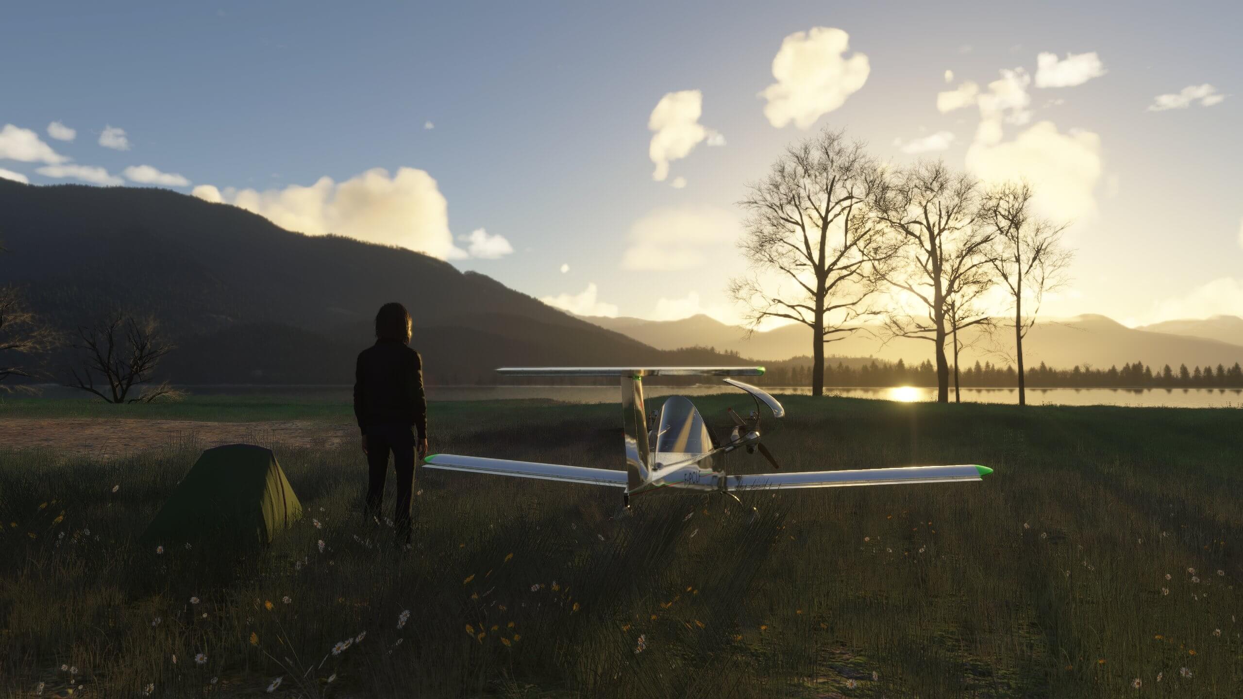 A camper admires the view of the sun rising over mountains next to their aircraft