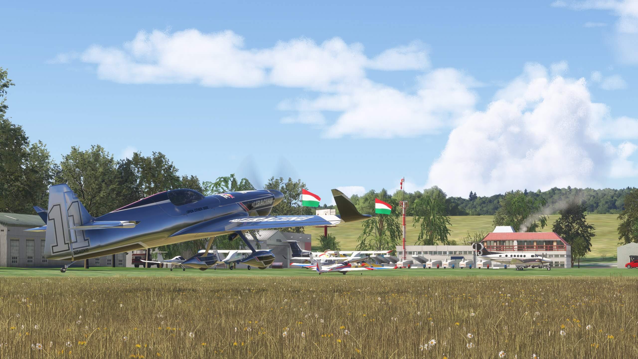 A race aircraft lifting off from a grass strip airport