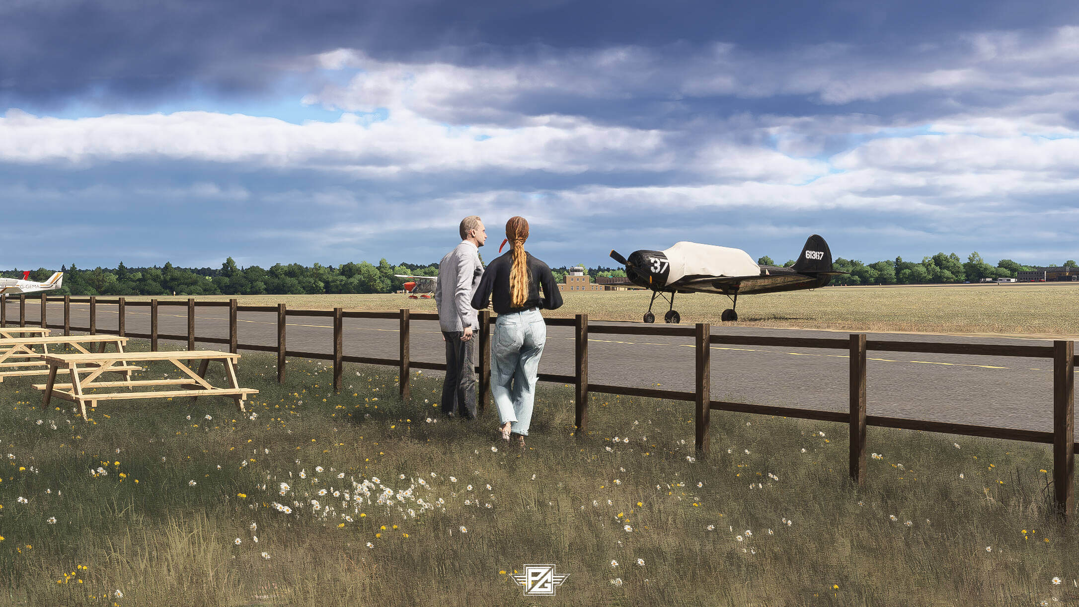 Two plane spotters look out over an airfield from behind a fence
