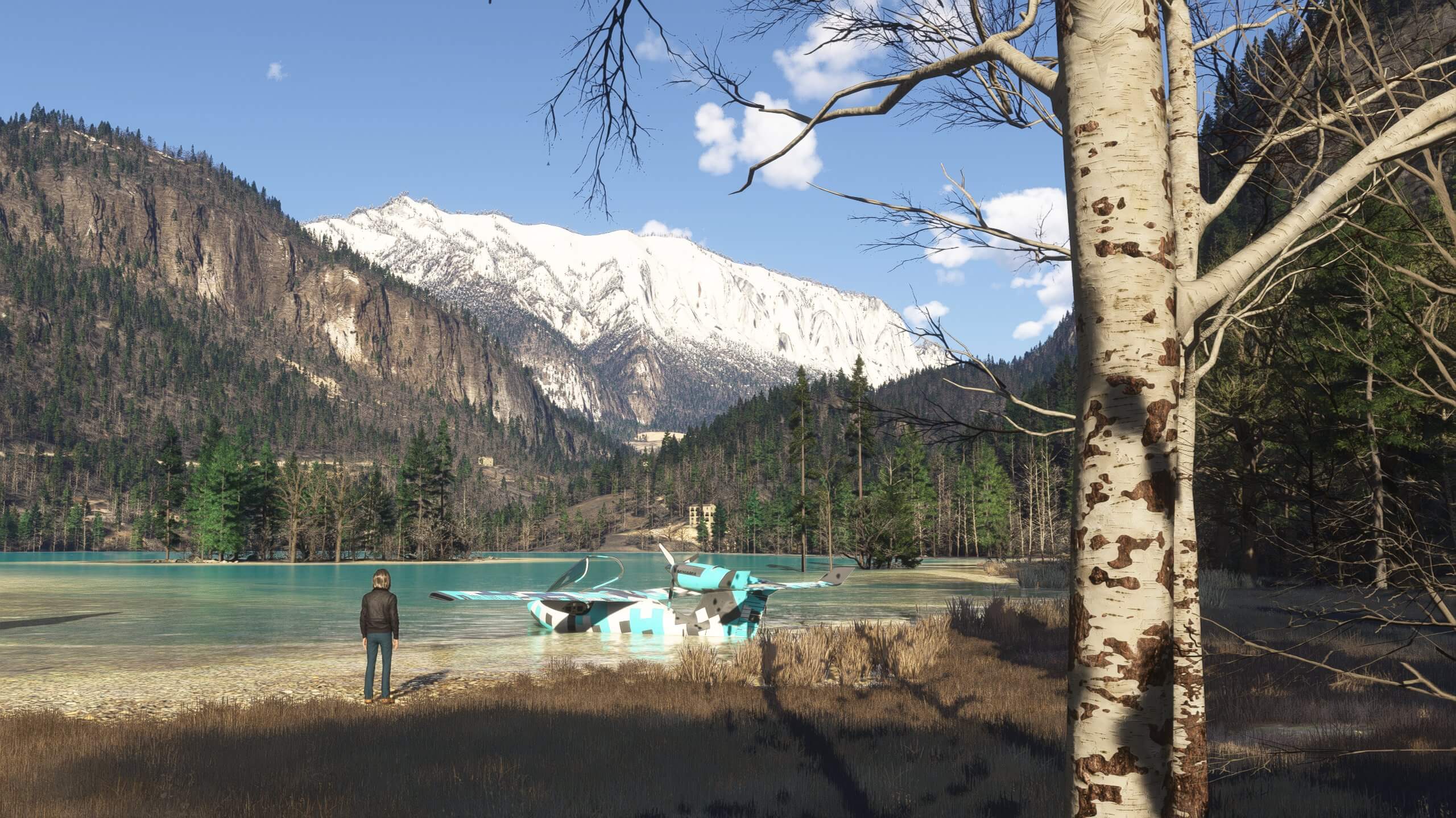 A pilot looks out towards their aircraft parked on a lake in a mountain range
