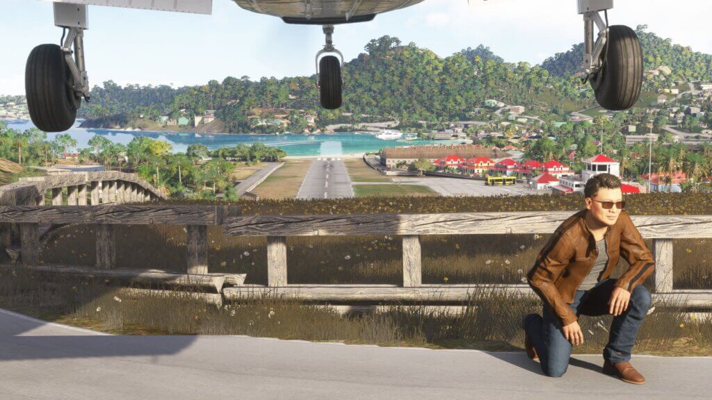 A man crouches down whilst a plane flies overhead on approach to St. Barths airport