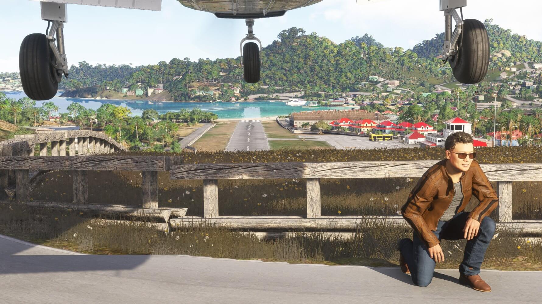 A man crouches down whilst a plane flies overhead on approach to St. Barths airport