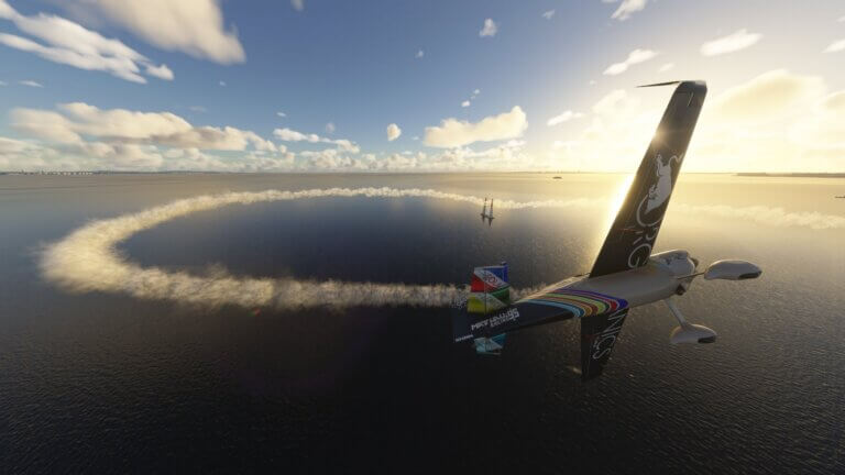 A Red Bull Air Race aircraft competes on a track over water, with smoke trail behind