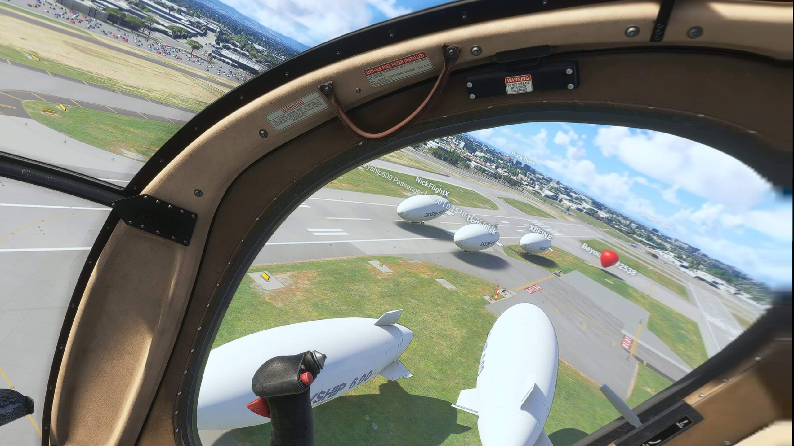 The view from a blimp as many other blimps sit on a runway