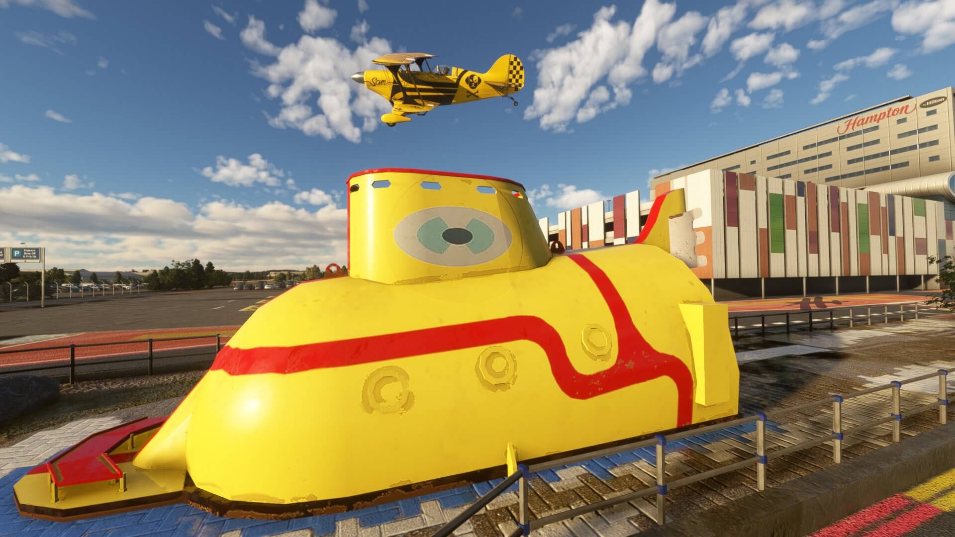 A yellow dual wing prop aircraft flies near The Beatles Yellow Submarine at Liverpool Airport