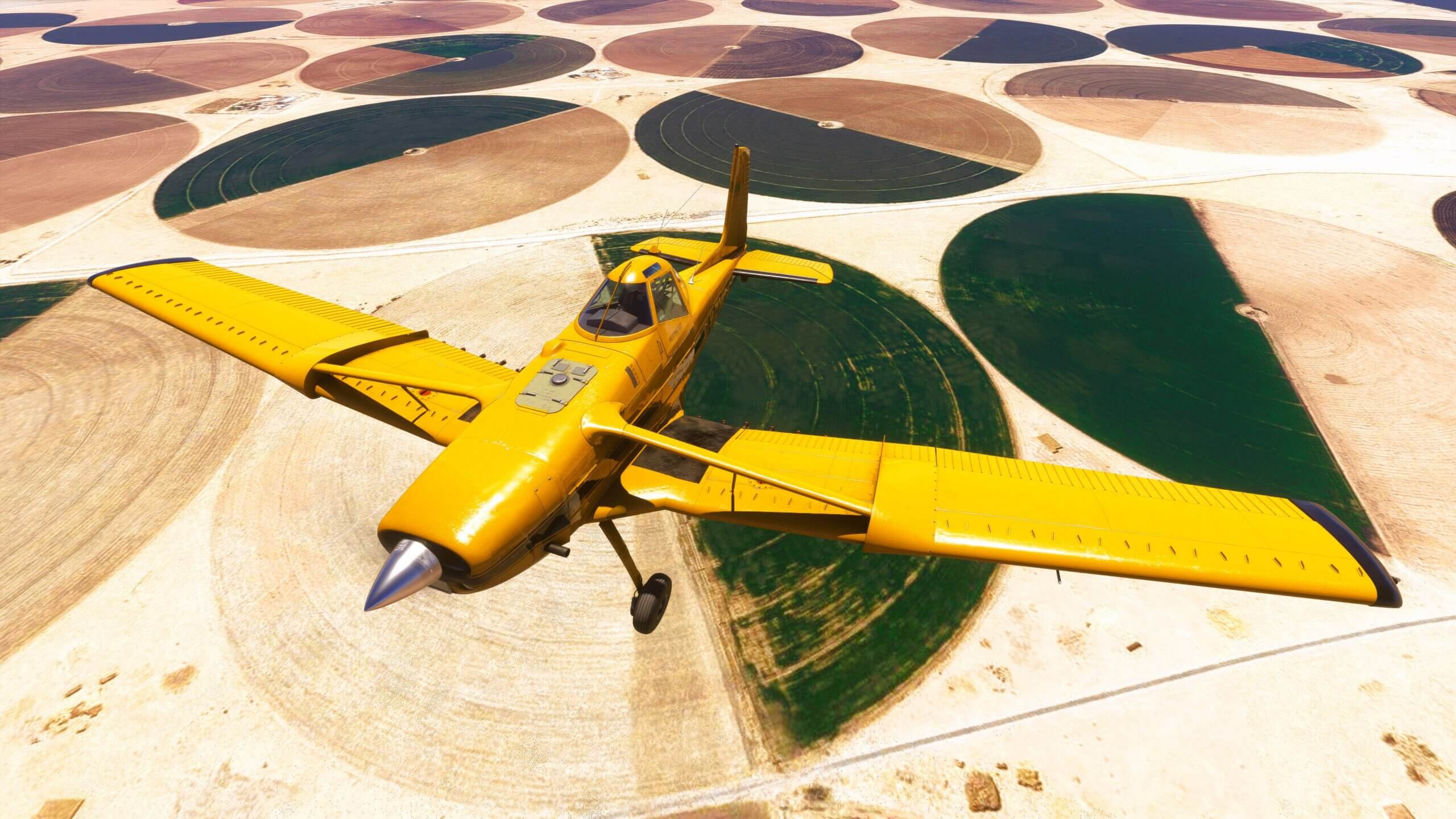 A crop duster flies over circular crop fields