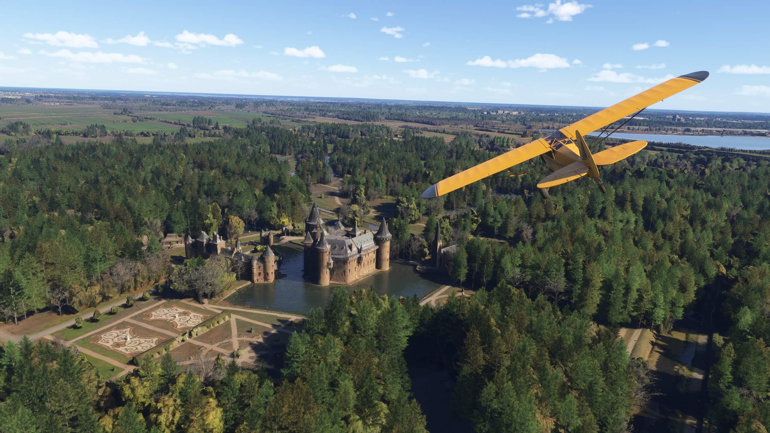 A yellow high wing propeller aircraft flies above a castle