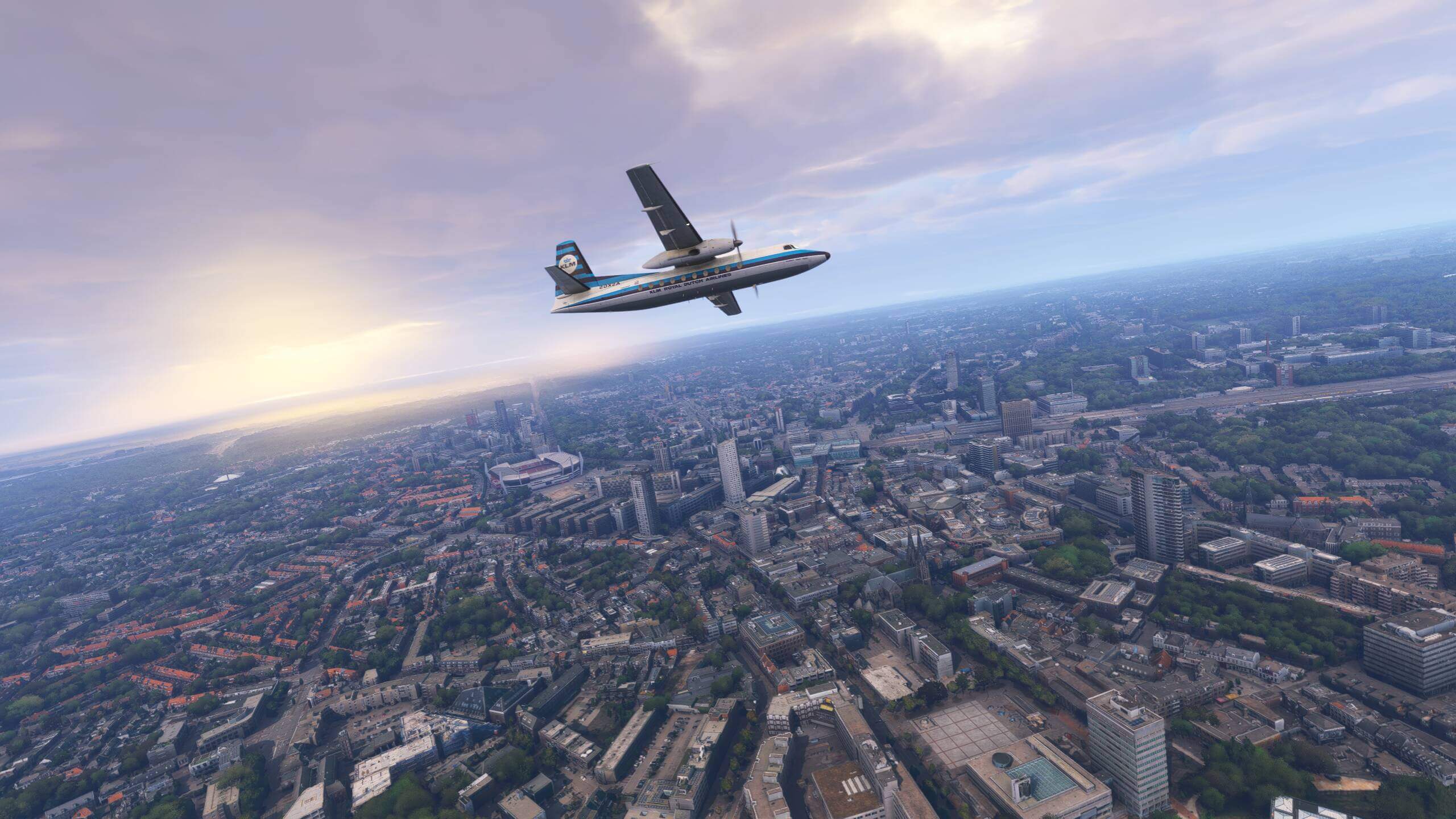A Fokker F27 in KLM livery flies over a city