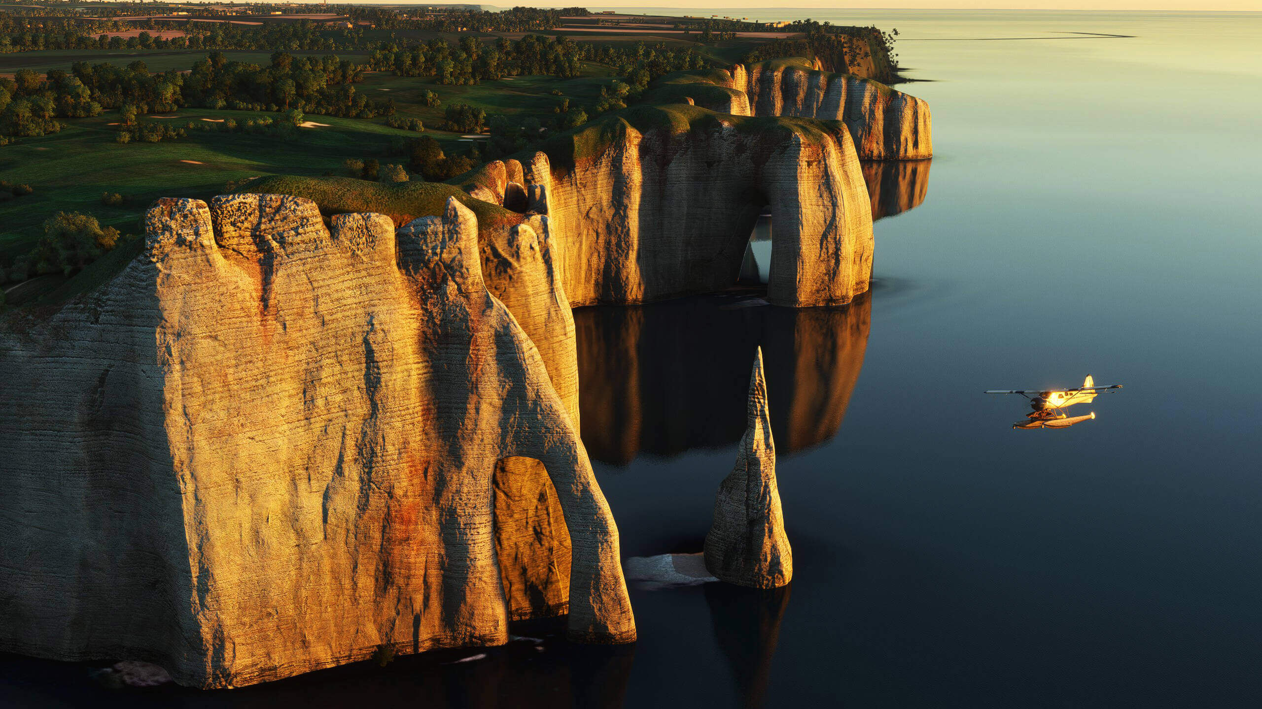 A high wing propeller aircraft flies near a steep cliffline