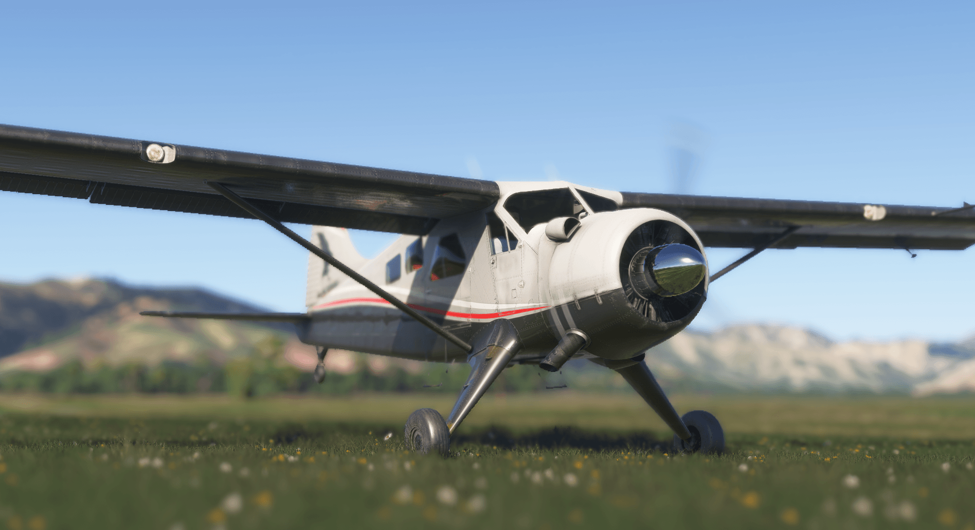 A high wing propeller aircraft sat on a grass strip runway