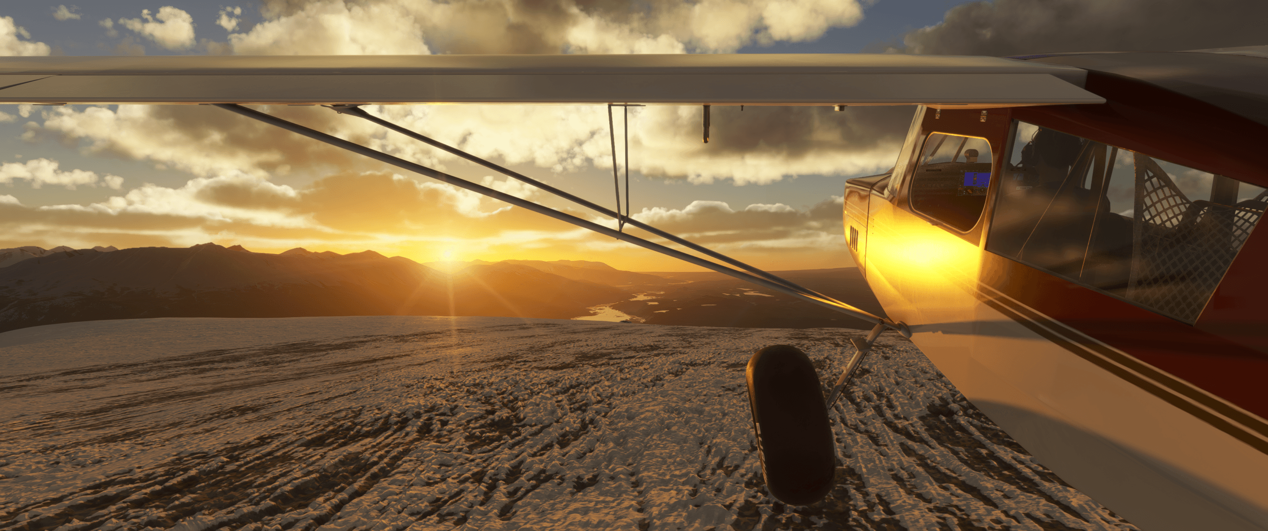 A high wing propeller aircraft parked on the edge of a mountain with the sun setting in the distance