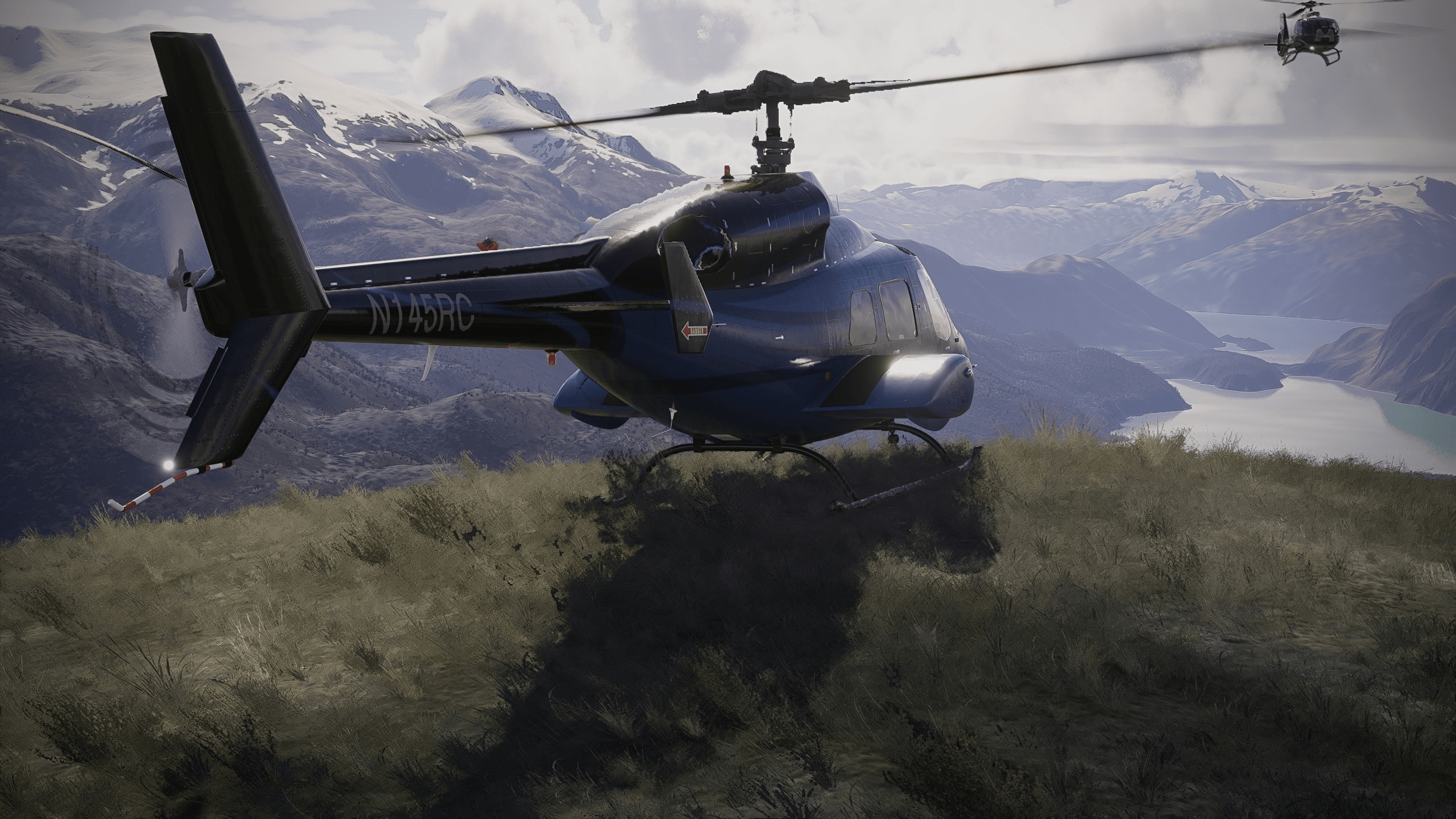 A helicopter parked on the edge of a cliff face with another helicopter hovering nearby