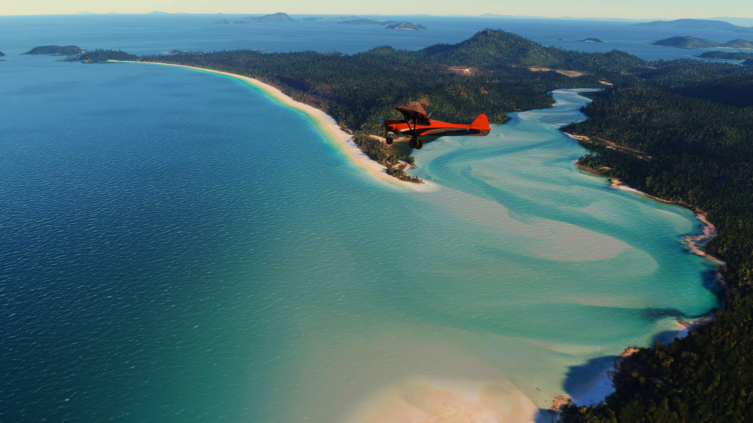 A high wing prop aircraft banks right flying over an island
