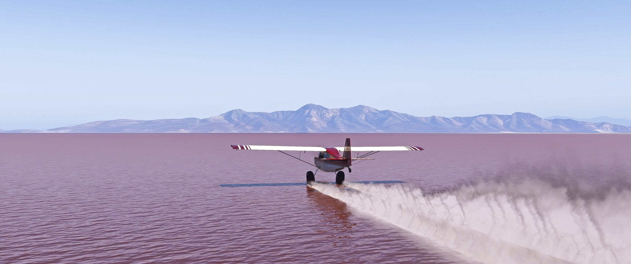 A high wing propeller aircraft skims the water of a flat lake