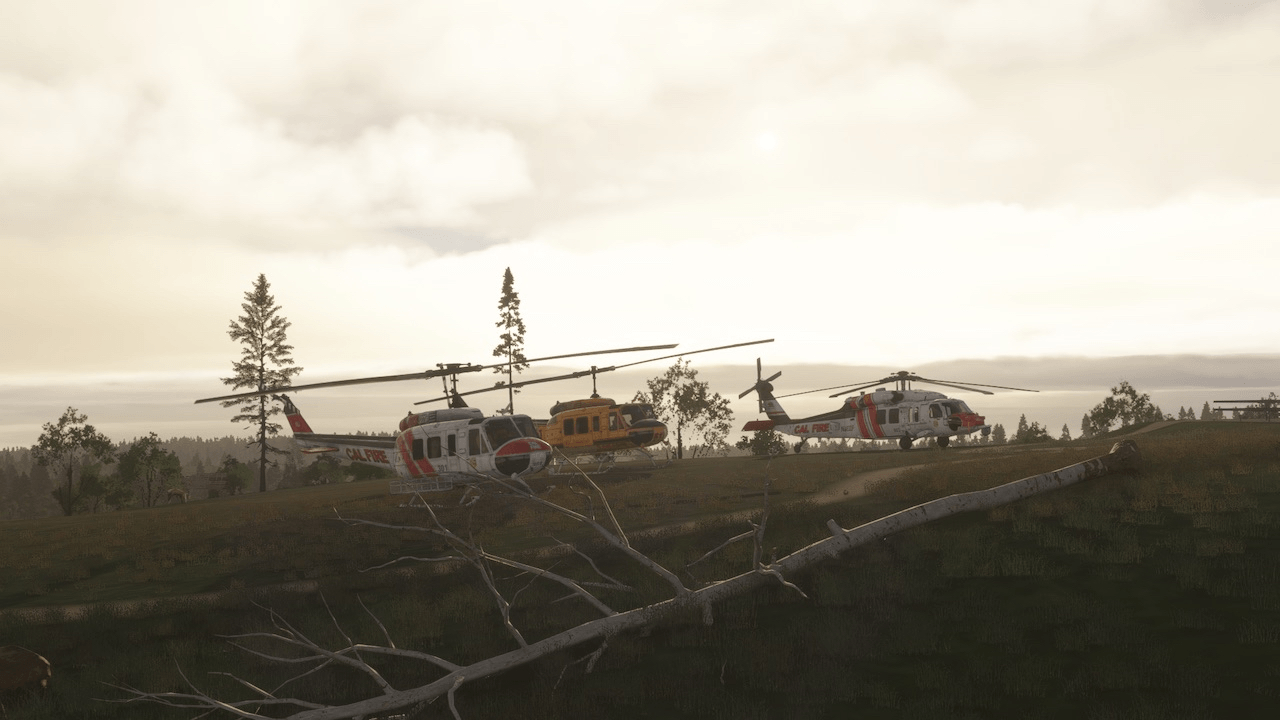A number of firefighting helicopters parked on the ground near a fire watch tower