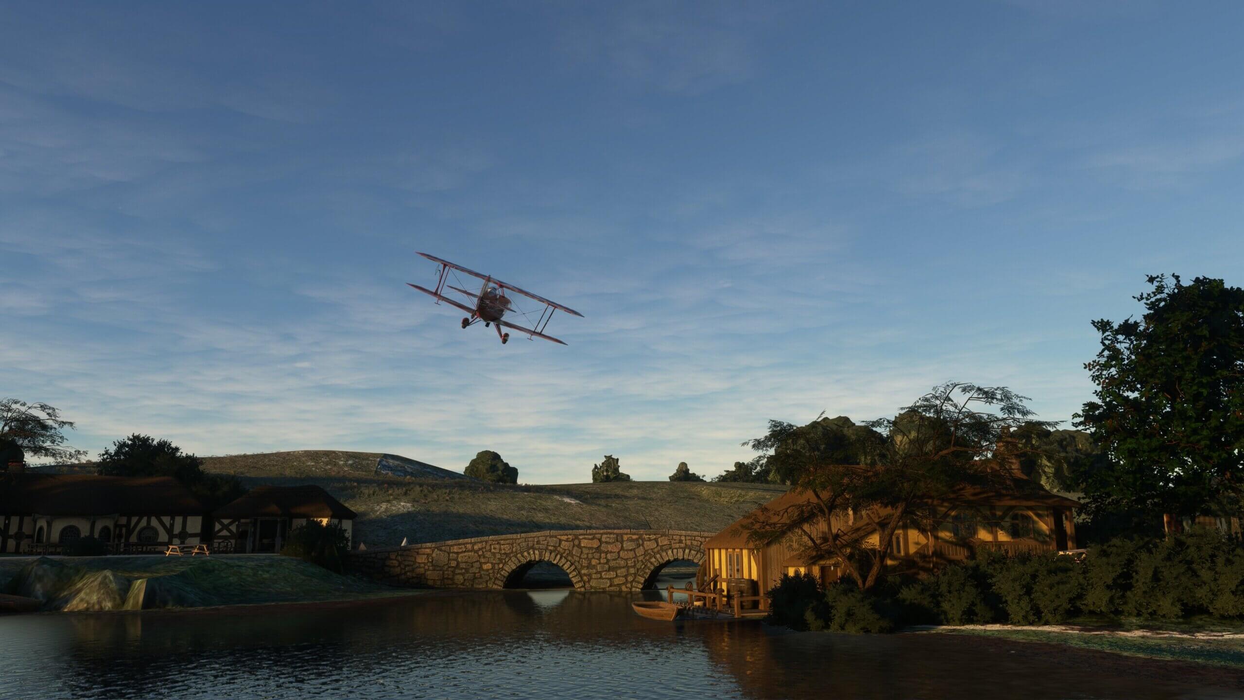 A dual wing red propeller aircraft flies over a lake hut