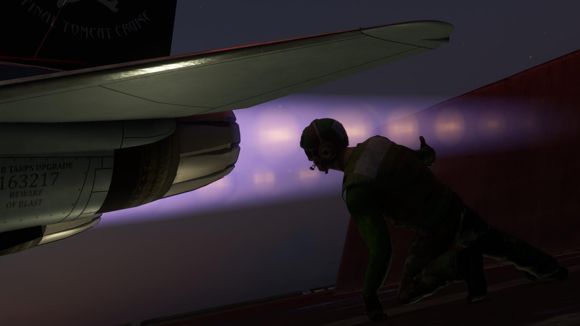An aircraft carrier worker kneels next to a fighter jet with afterburner engaged before launch
