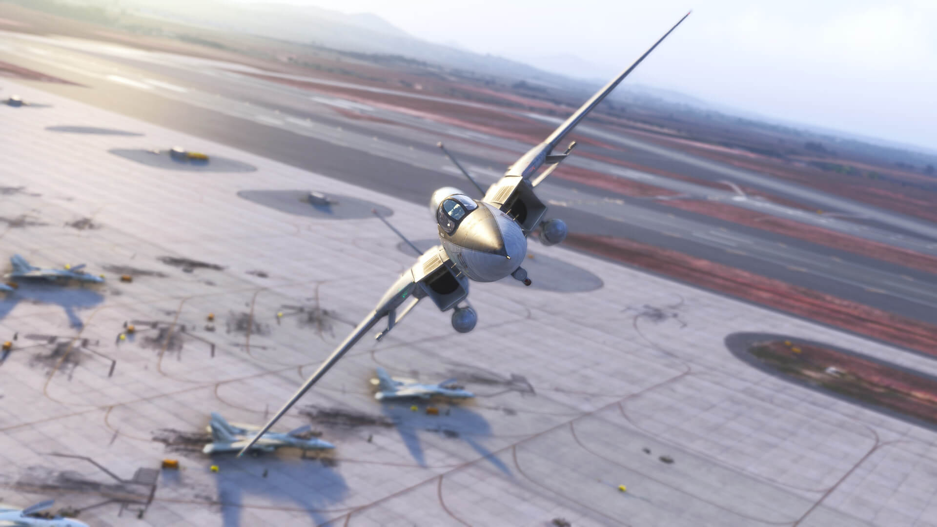 An F-14 banks heavily to the right while flying over the apron of a military airport