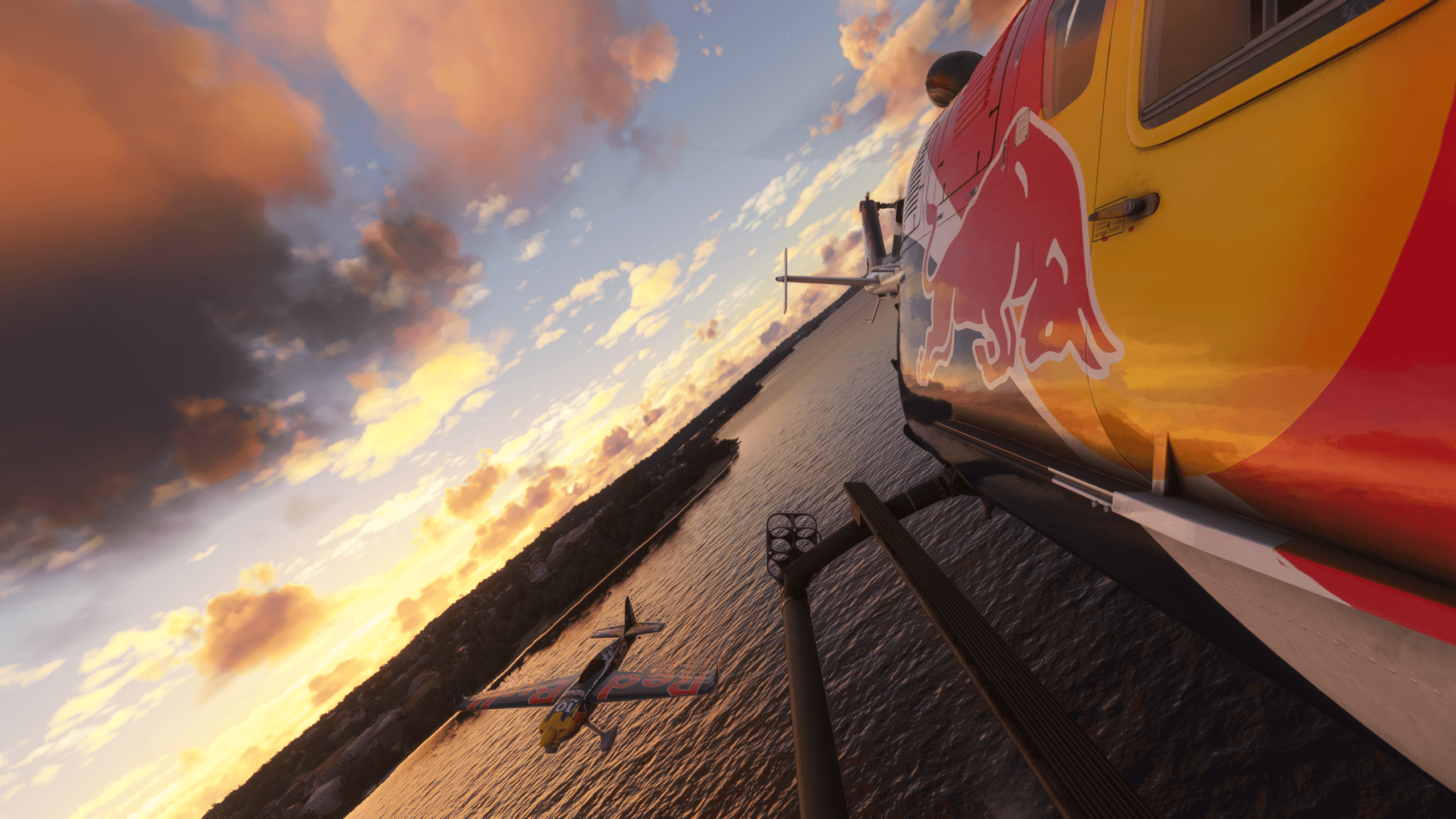 A MB105 helicopter flies in close formation with an Extra 300 aerobatic aircraft, painted in Red Bull colors