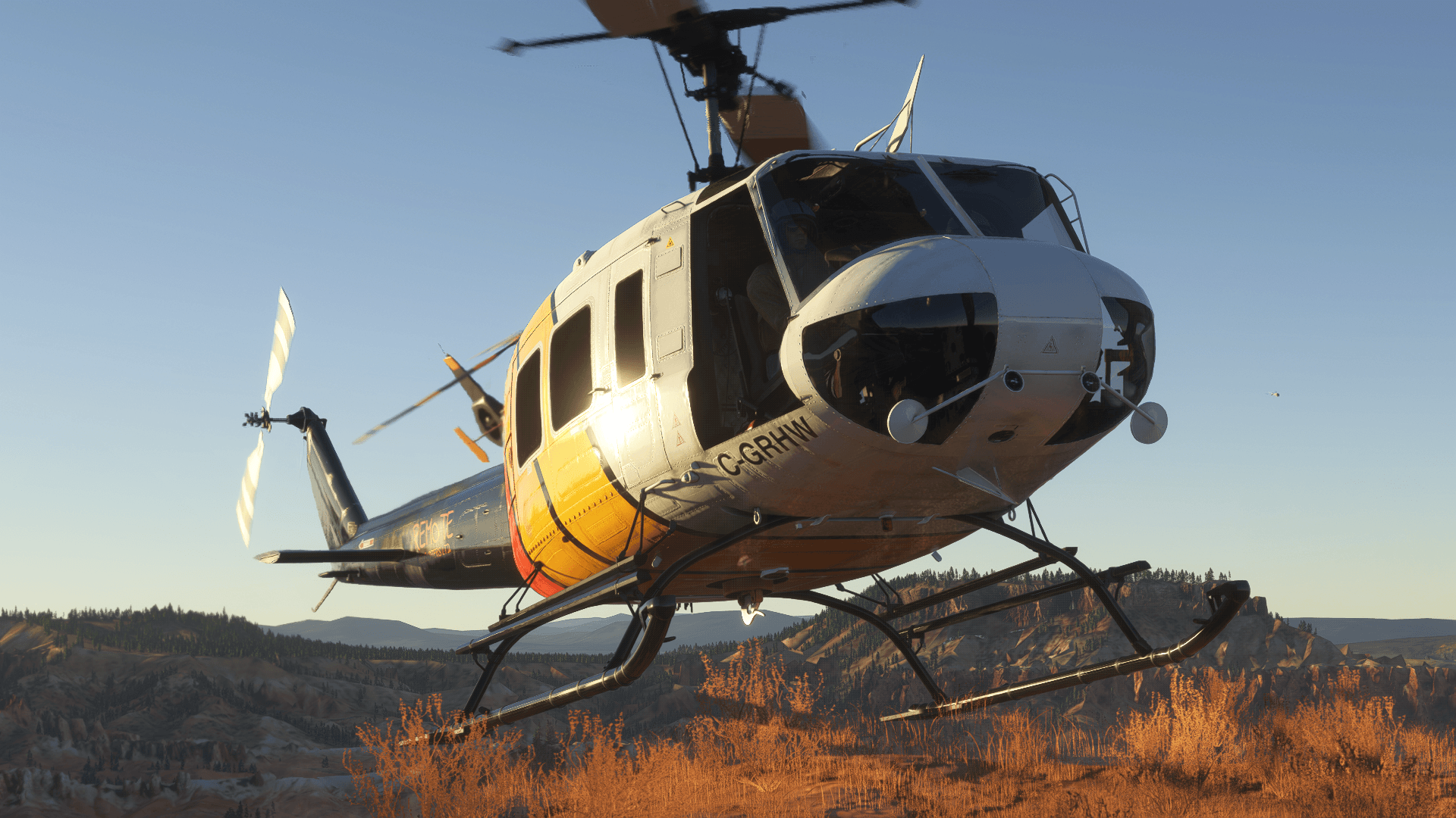 A helicopter just about to touchdown on rough desert terrain