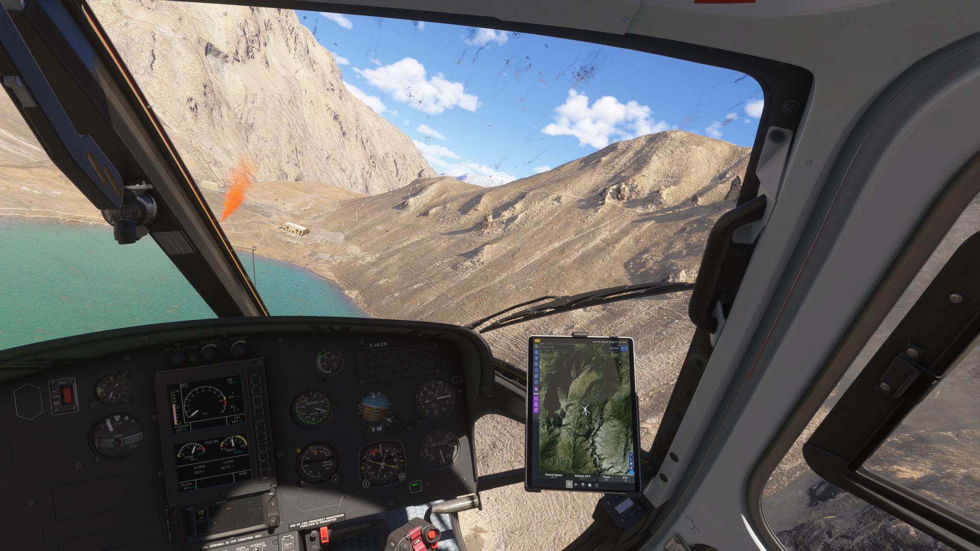The view from a helicopter approaching a landing site marked with orange smoke