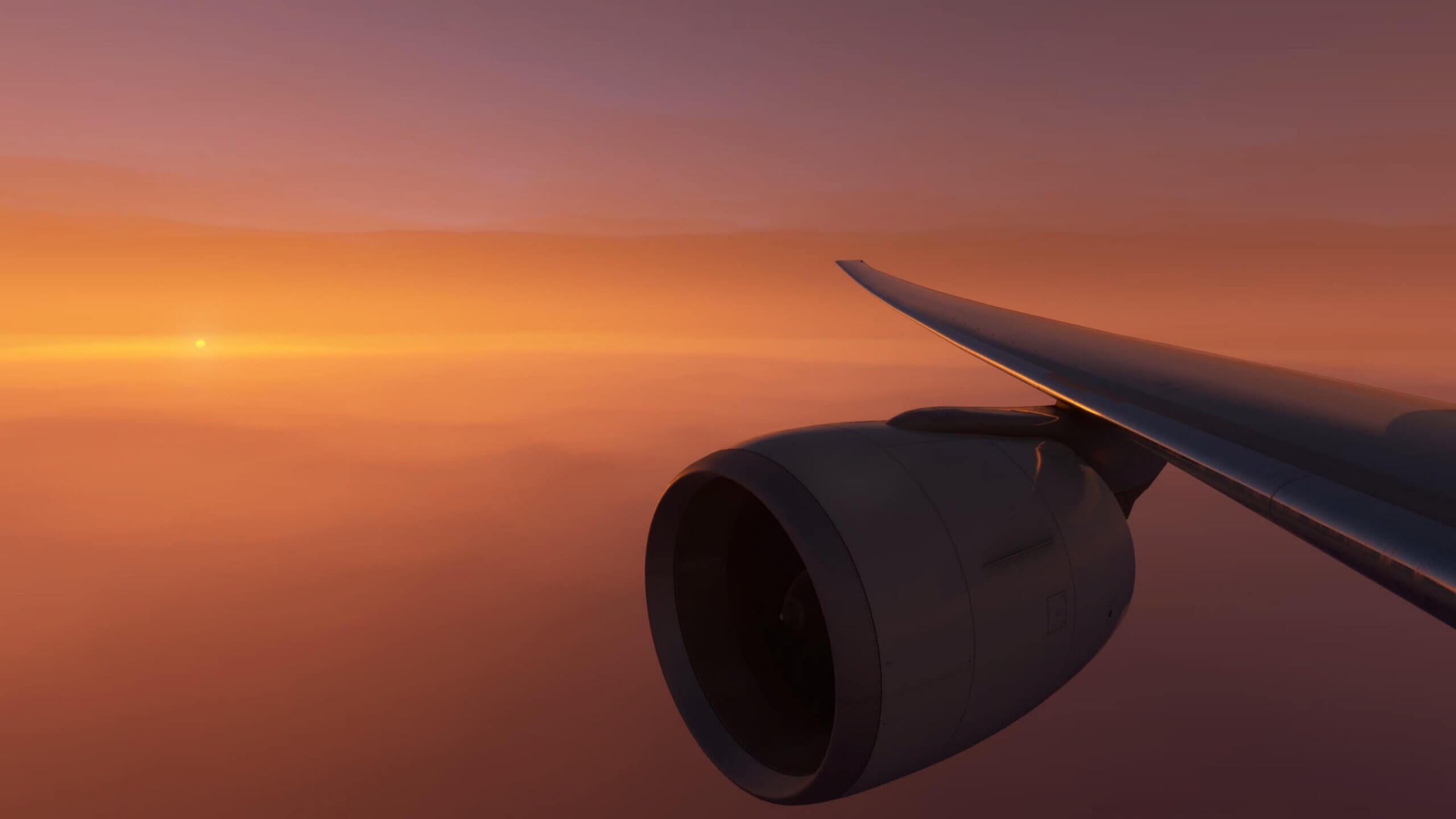 The wing view from a Boeing 777 with the sun in the distance during golden hour