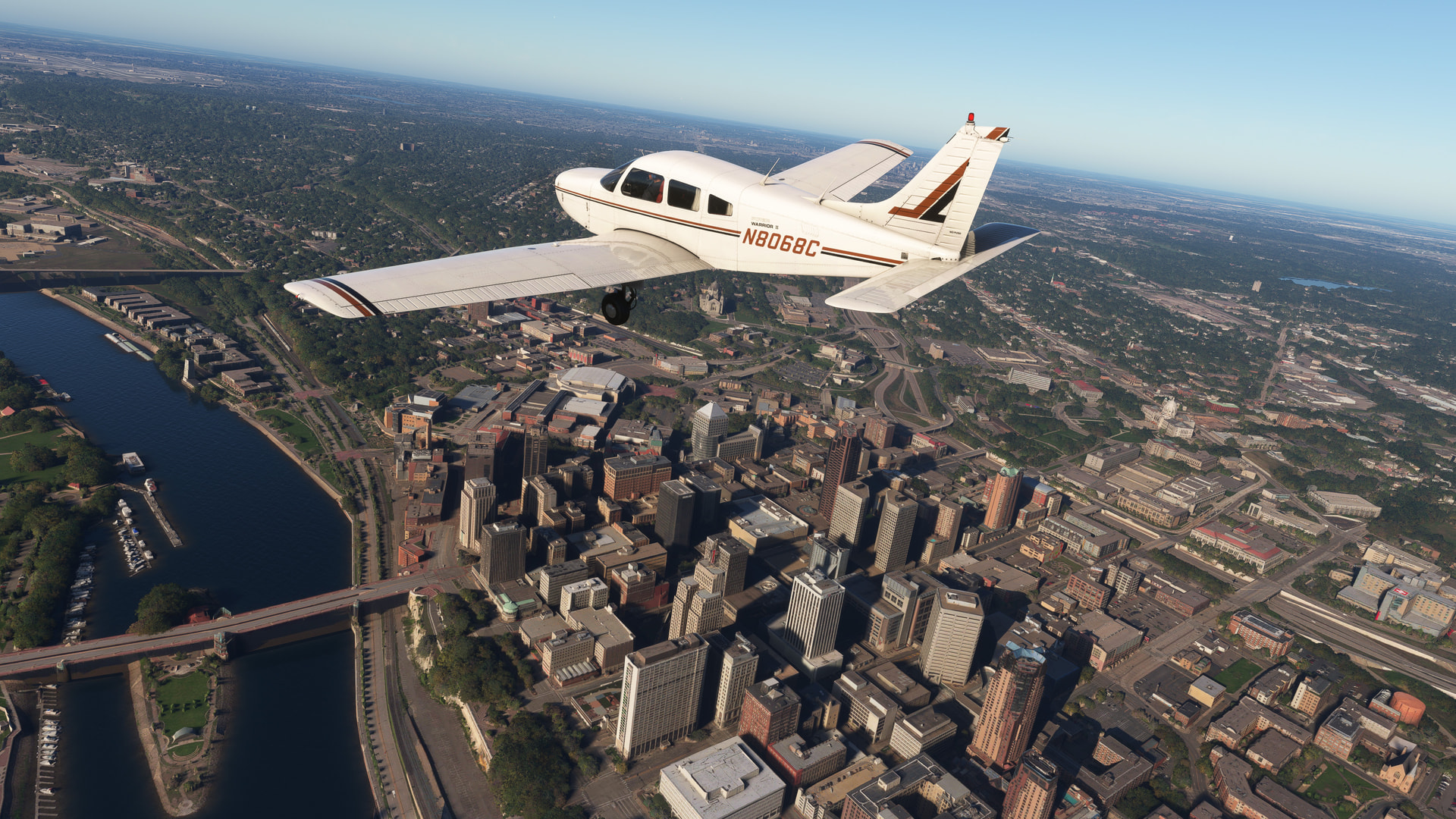 A low wing Piper Warrior flies over a city skyline