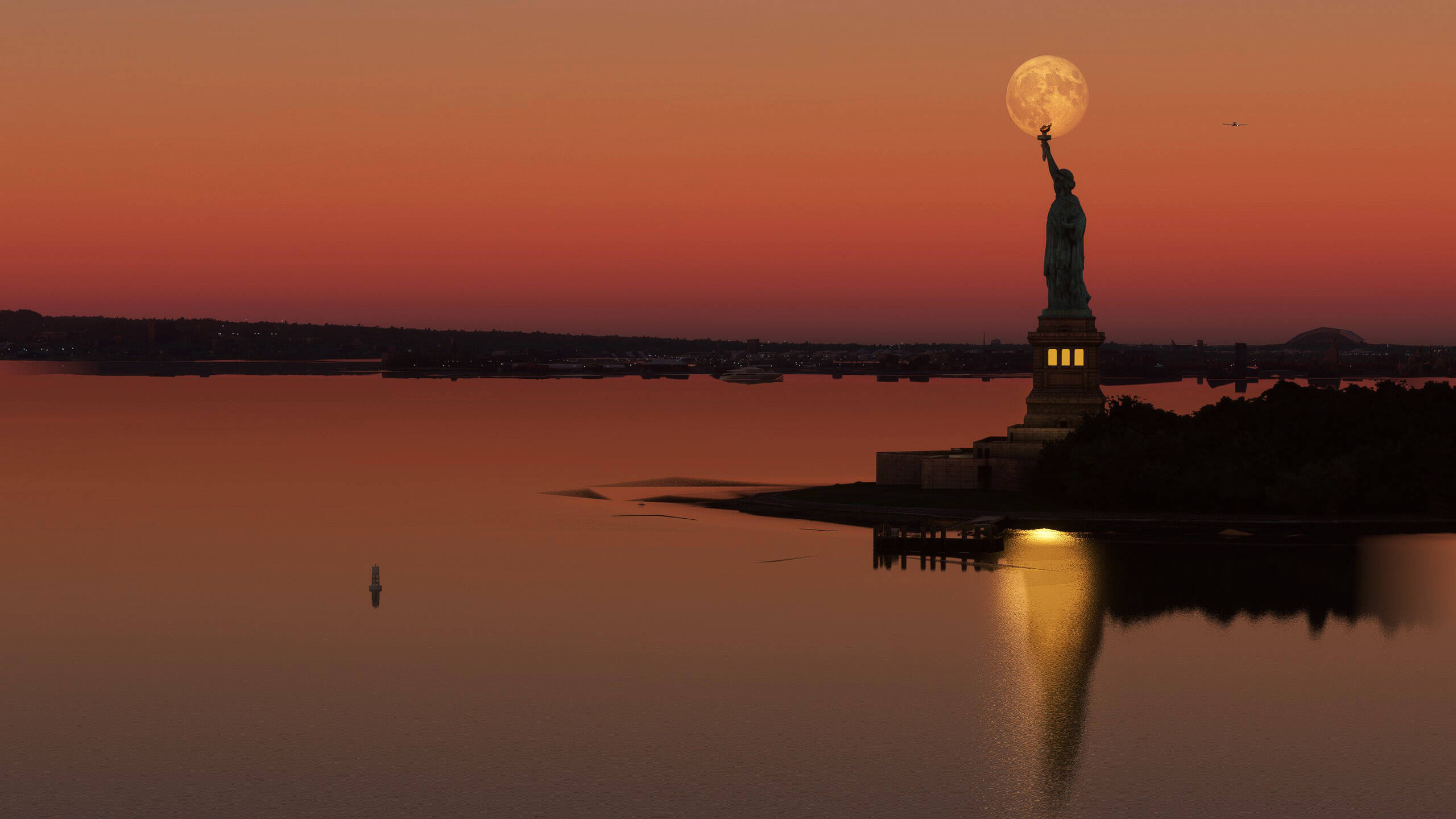 The Statue of Liberty in front of the moon during golden hour