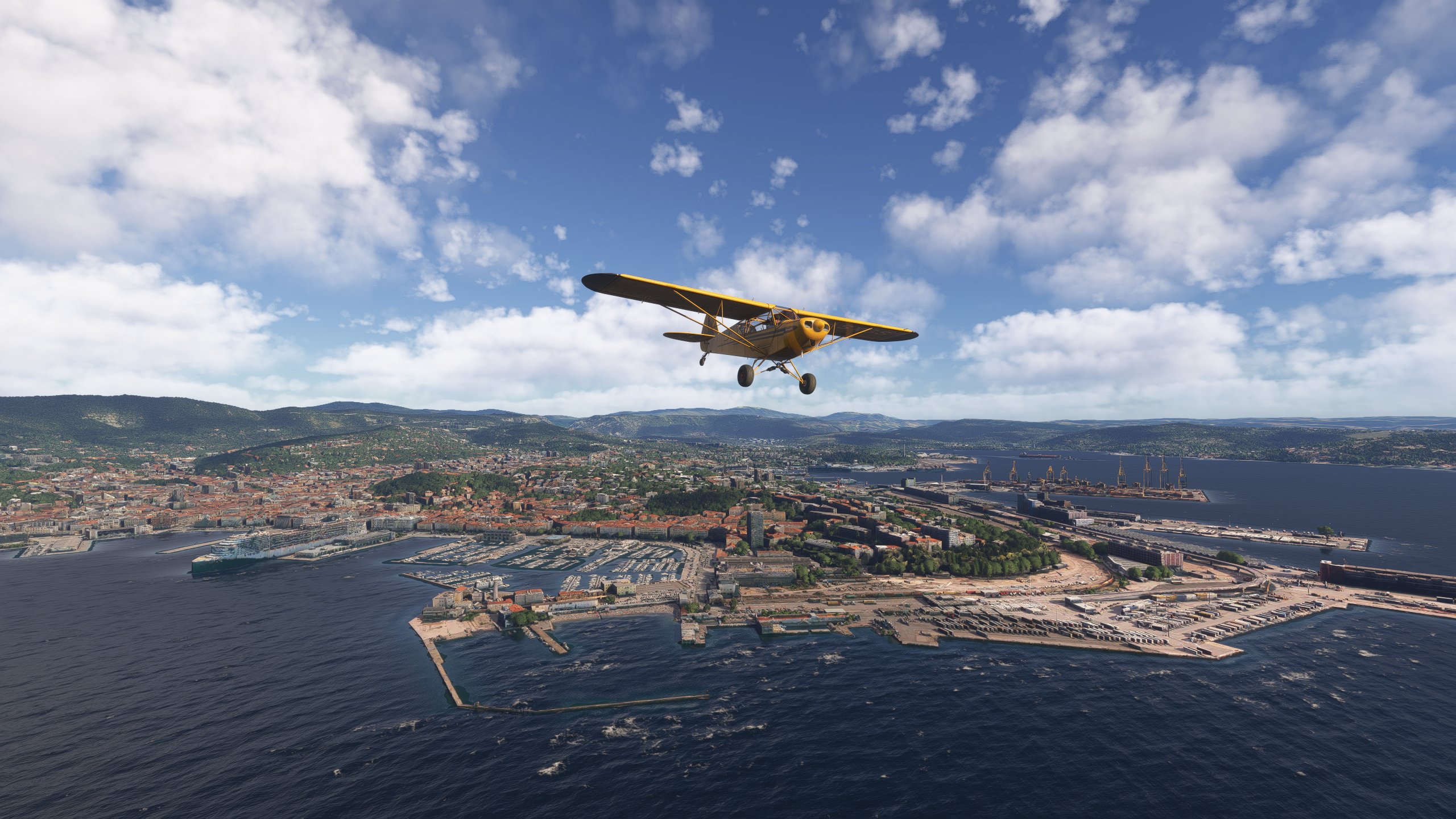 A high wing yellow propeller aircraft flies over the coast of a city