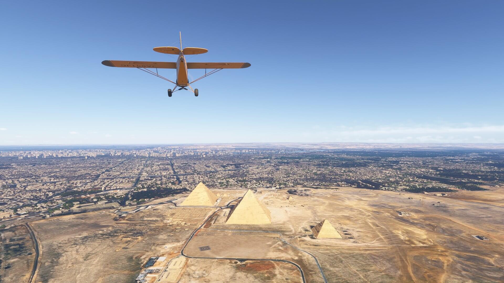 A yellow high wing aircraft flies over the Pyramids of Giza, Cairgo