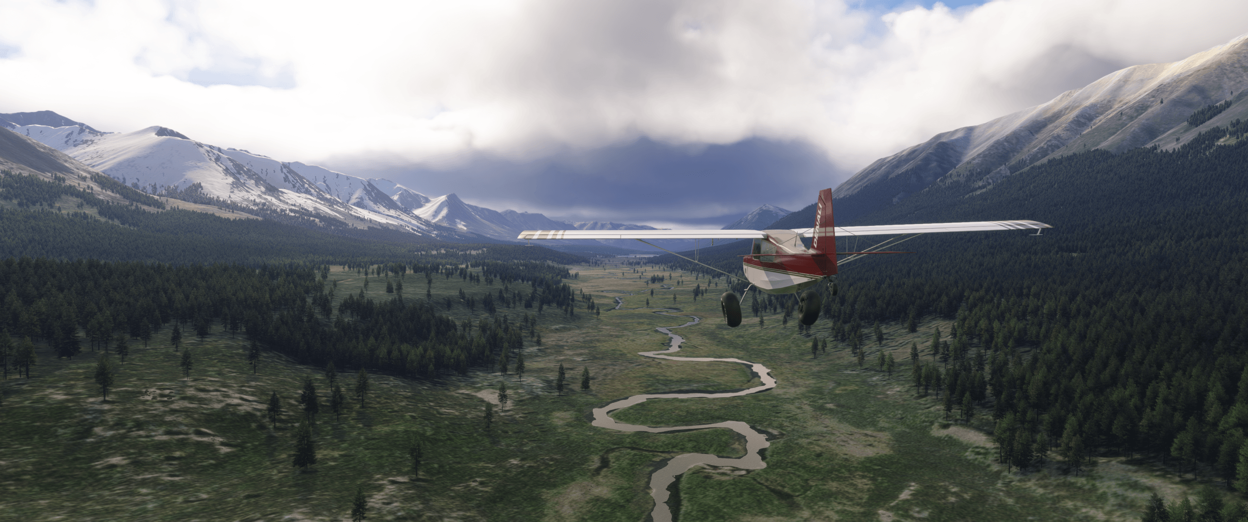 A high wing propeller aircraft follows a river through a valley
