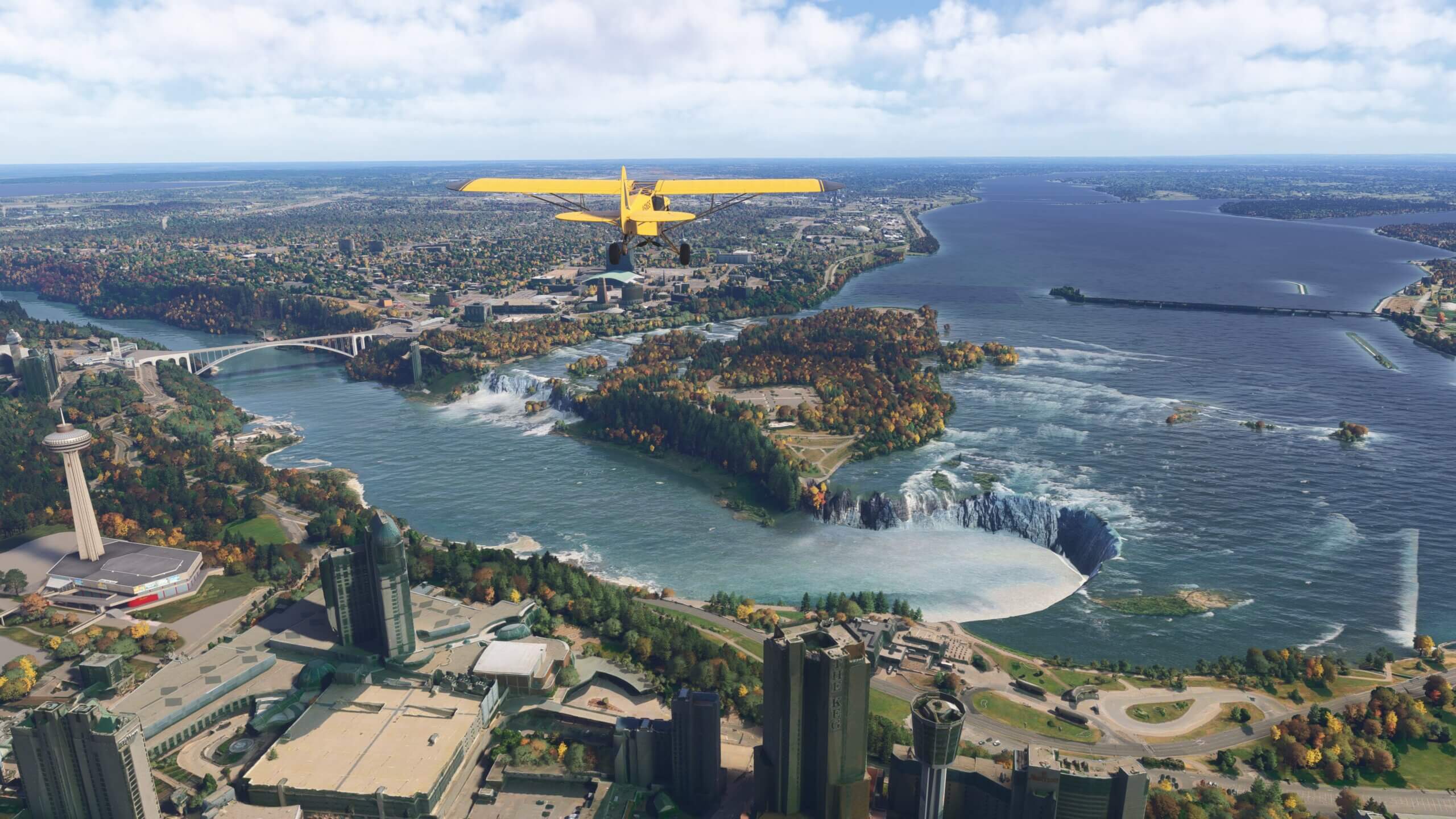 A yellow high-wing aircraft flies over the Niagara Falls